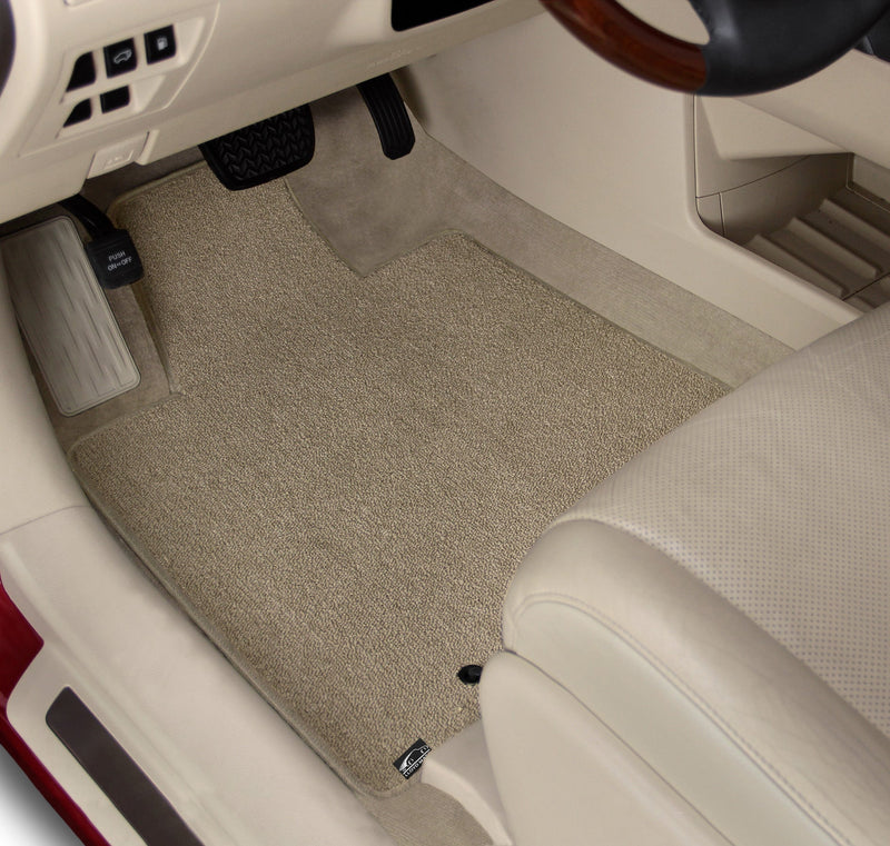 Car interior with beige floor mats and a steering wheel.