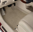 Car interior with beige floor mats and a steering wheel.