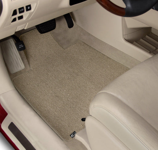 Car interior with beige floor mats and a steering wheel.