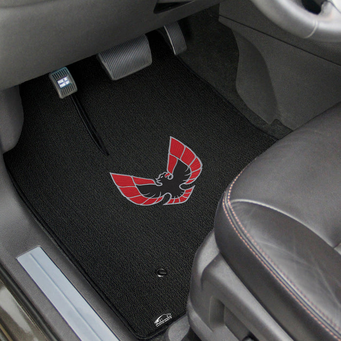 Car floor mat with a logo on the driver's side, inside a vehicle.