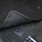 Close-up of a car's gear shift area with a carbon fiber pattern.