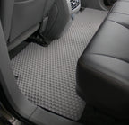 Car interior with a gray floor mat and black leather seat.