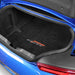 Car trunk with black floor mats featuring a logo, open on a blue car.