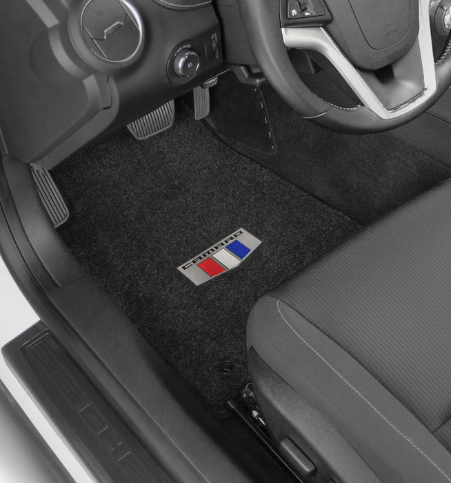 Car interior with black floor mats featuring a logo on the driver's side.