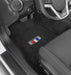Car interior with black floor mats featuring a logo on the driver's side.