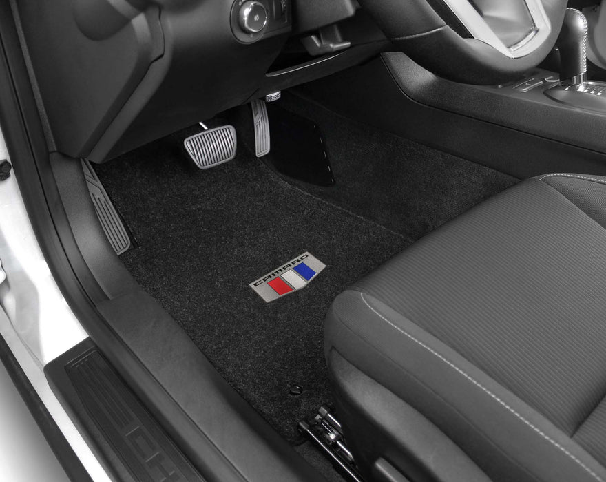 Car interior with black floor mats featuring a logo on the driver's side footwell.