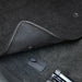Close-up of a car's gear shift area with a textured cover and metallic elements.