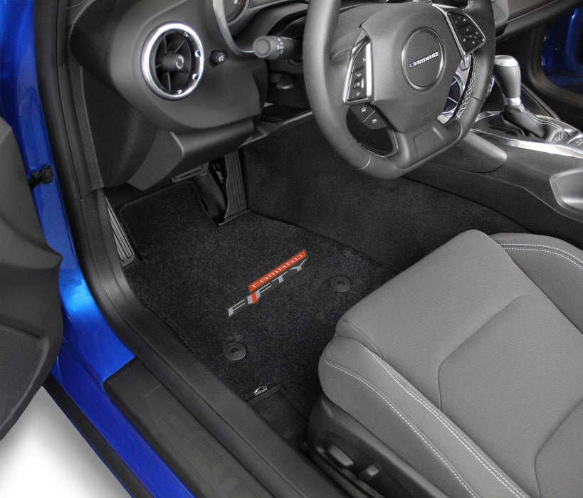 Car interior with black floor mats featuring a brand logo.