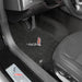 Car interior with black floor mats featuring a logo on the driver's side.