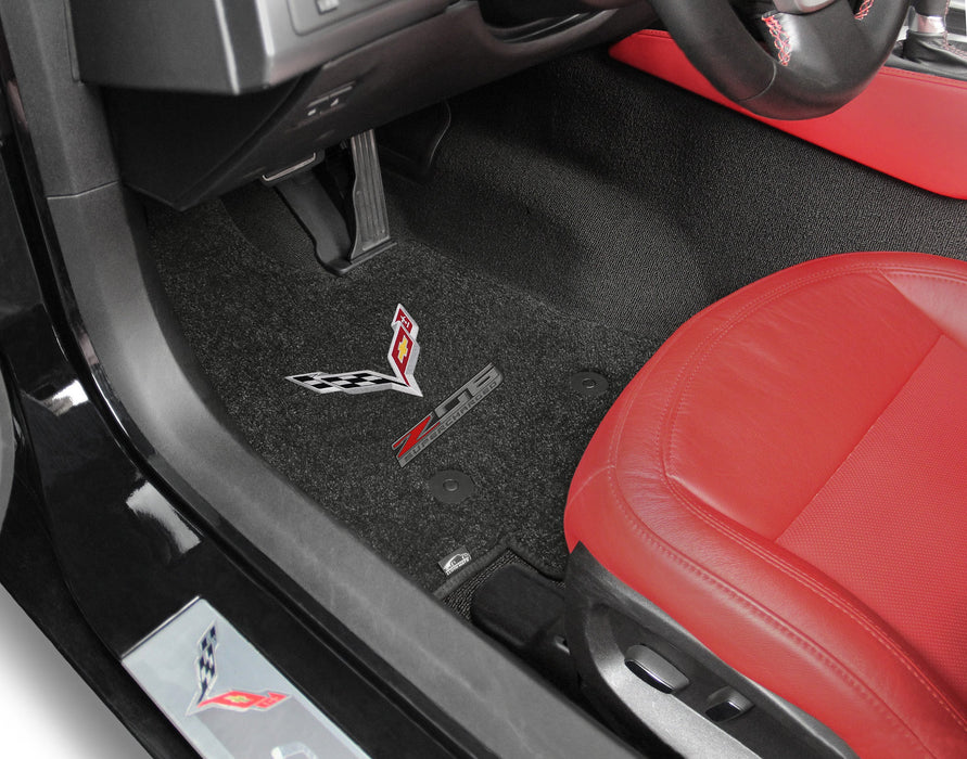 Car interior with red seat and black floor mat featuring a logo.