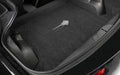 Car trunk with a black carpeted floor mat featuring a brand logo.