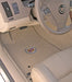 Car interior with beige carpeted floor mats featuring a logo, steering wheel, and dashboard.