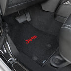 Black car floor mats with red 'Jeep' logo on a vehicle interior.