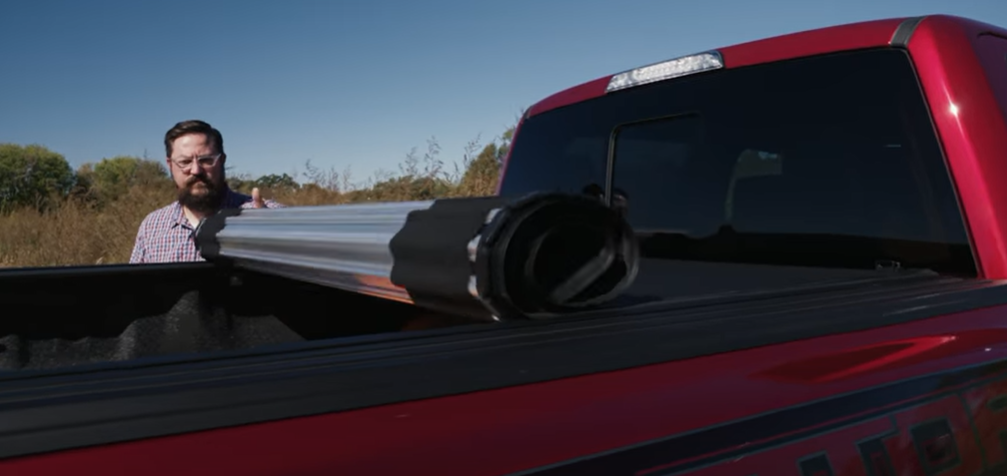 A truck owner rolling down his hard roll-up cover