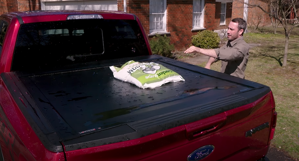 Someone throwing a bag of cement on a Bak Vortrak Retractable Tonneau Cover