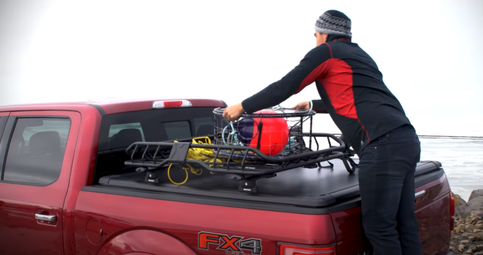 A truck owner loading cargo on a track system installed over a tonneau cover