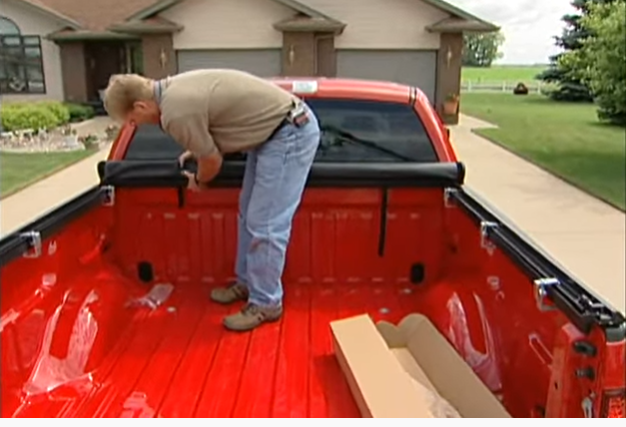 Man releasing the safety straps and unrolling the Truxport cover